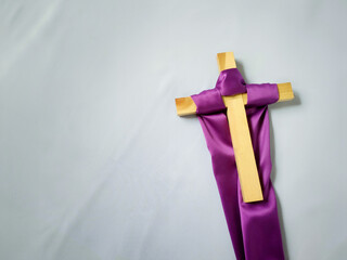 Lent Season,Holy Week and Good Friday concepts - photo of purple cloth cling to wooden cross in vintage white background. Stock photo.
