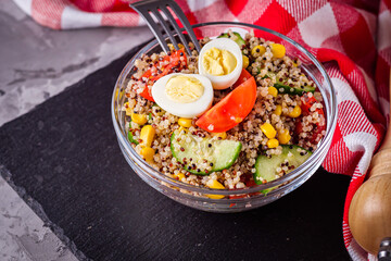 bowl of healthy quinoa with vegetables on a dark rustic background