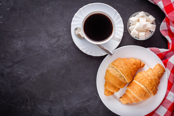delicious fresh croissant and cup of coffee on a dark stone rustic background