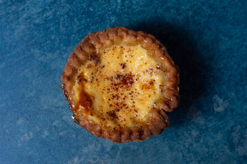 Fresh egg custard tart on a stone blue background