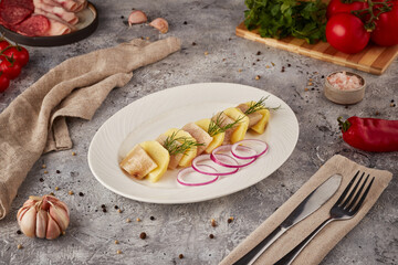 Herring slices with potatoes, textured background