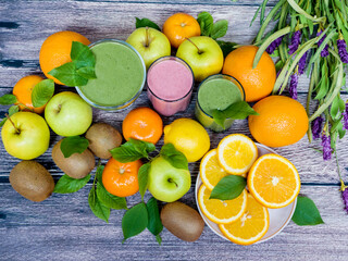 Group of fresh fruits on a wooden background and three glasses of smoothies. Detox. The right food