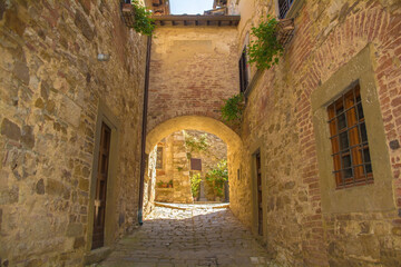 Fototapeta na wymiar A stone archway across a quiet residential street in the historic medieval village of Montefioralle near Greve in Chianti in Florence province, Tuscany, Italy 