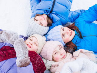 A group of joyful children in bright packaging and knitted hats in winter lie in the snow and look up