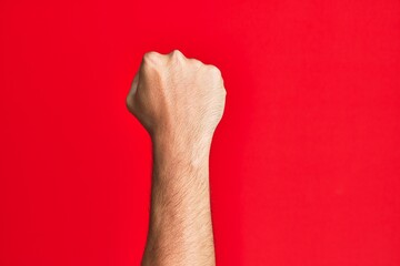 Arm of caucasian white young man over red isolated background doing protest and revolution gesture,...