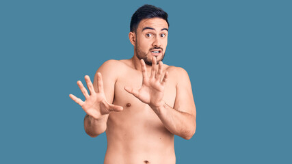 Fototapeta premium Young handsome man wearing swimwear afraid and terrified with fear expression stop gesture with hands, shouting in shock. panic concept.