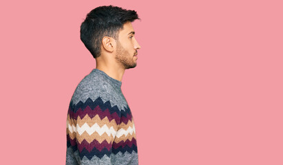 Young handsome man wearing casual winter sweater looking to side, relax profile pose with natural face with confident smile.