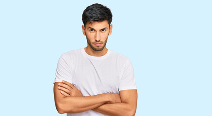 Fototapeta premium Young handsome man wearing casual white tshirt skeptic and nervous, disapproving expression on face with crossed arms. negative person.