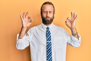 Handsome man with beard and long hair wearing business clothes relax and smiling with eyes closed doing meditation gesture with fingers. yoga concept.