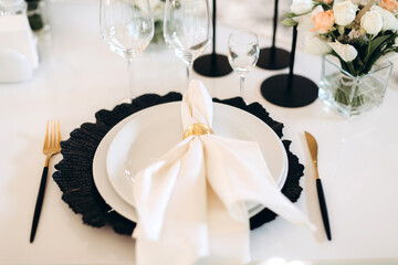decoration of a wedding table, table setting for a wedding, white dishes on a wedding table with elements of gold leaves, themed decor