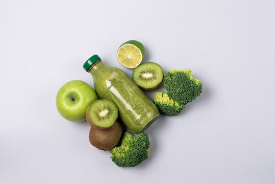 Glass Bottle of Fresh Green Smoothie with Kiwi Broccoli Green Apples Lime and Babanas Healthy Detox Drink Blue Background Top View