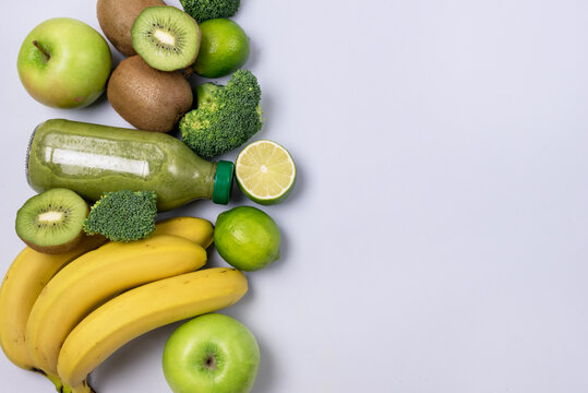 Glass Bottle of Fresh Green Smoothie with Kiwi Broccoli Green Apples Lime and Babanas Healthy Detox Drink Blue Background Top View