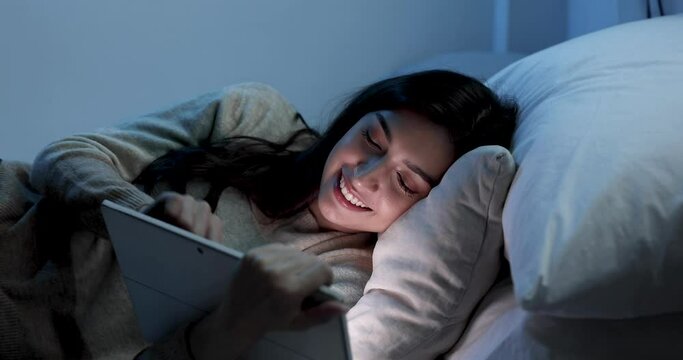 Caucasian women are using the tablet computer on the bed before she sleeping at night, Mobile addict concept, Blue light harmful to the eyes.