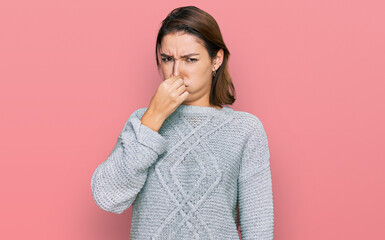 Young caucasian girl wearing casual clothes smelling something stinky and disgusting, intolerable smell, holding breath with fingers on nose. bad smell - obrazy, fototapety, plakaty