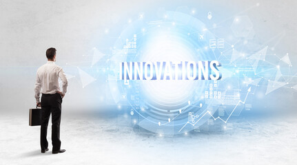 Rear view of a businessman standing in front of INNOVATIONS inscription, modern technology concept