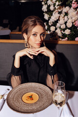 beautiful woman with dark hair in elegant dress posing in luxury restaurant