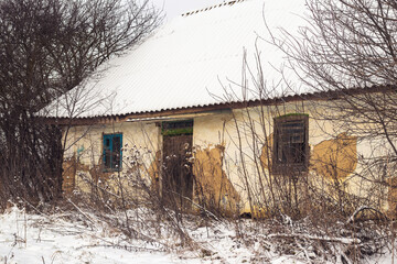 Old rural abandoned house with peeling plaster in winter