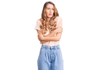 Young beautiful caucasian woman with blond hair wearing casual clothes shaking and freezing for winter cold with sad and shock expression on face