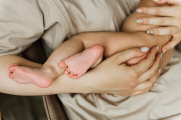 The foot of the newborn close-up on the mother's hand.