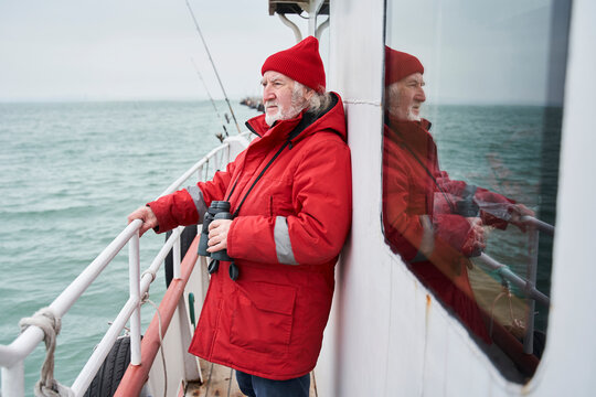 Captain Of Fishing Boat Holding His Binoculars While Looking Away