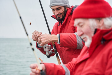 Colleagues standing on a boat with fishing rod and hook the bait