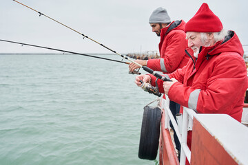Two man together fishing from a boat at winter