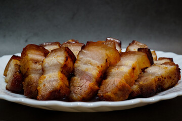 Salt and pepper, and Gochujang Korean sauce grilled pork belly on a white dish with a dark background