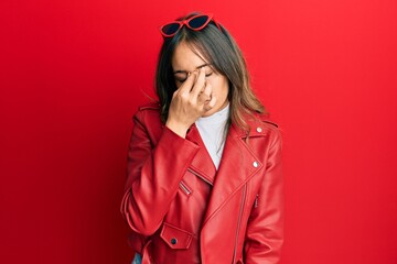 Young brunette woman wearing red leather jacket tired rubbing nose and eyes feeling fatigue and headache. stress and frustration concept.