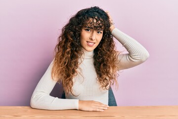 Young hispanic girl wearing casual clothes sitting on the table confuse and wonder about question....