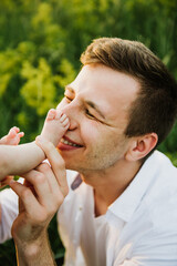 Naklejka premium Young dad kisses the feet of a newborn close-up.