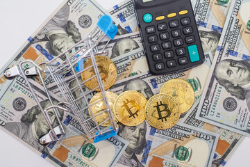 Fototapeta premium Bitcoins with calculator and shopping cart on the background of dollars.