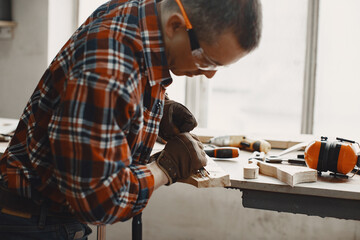 Craftsman cutting a wooden plank. Worker with wood. Man in a cell shirt.