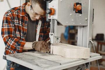 Wood cutting with circular saw. Closeup of mature man sawing lumber.
