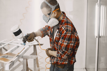 Yooung repairman carpenter working with paint painting. Master painter in a factory painting wood...