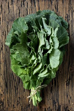 Green Collard bunch of leaves on rusty background. organic nutrition concept. raw foods kale. Raw Green Organic Collard Greens