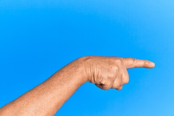 Hand of senior hispanic man over blue isolated background pointing with index finger to the side, suggesting and selecting a choice