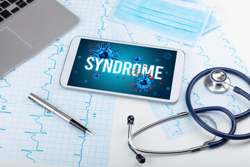 Tablet pc and doctor tools on white surface with SYNDROME inscription, pandemic concept