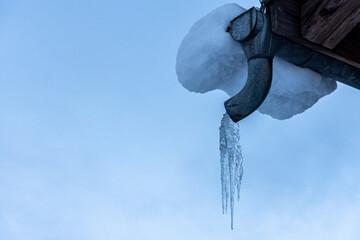 icicles attached to the end of a gutter on a roof