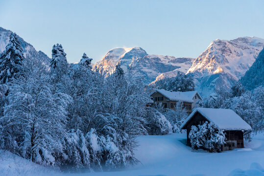 Winter landscape in Glarus Süd with Chalets and farms with mount Tödi, in the Alps, in the background 