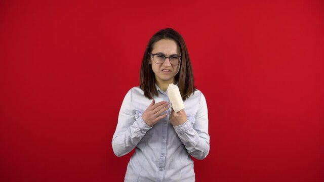 The young woman's index finger with a bandage is in pain. Shooting on a red background.