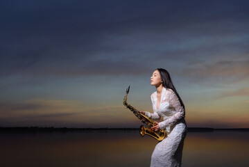 Saxophone, music instrument played by saxophonist player musician  in lake on during sunset