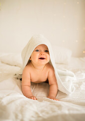 smiling little baby girl in a white bath towel lying on the bed