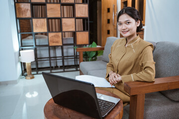 woman in government servant uniform sitting on the couch during online meeting using a laptop...