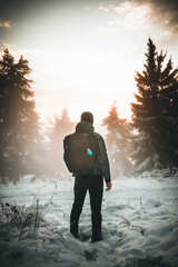 winter landscape forest backpack man / traveler in modern winter clothes in the forest, traveling in the mountains