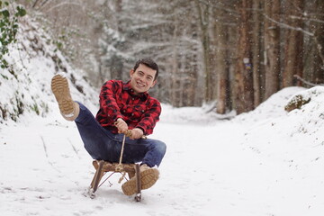 Back to childhood - Happy man riding a sledge, having fun and laughing