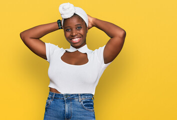 Young african woman with turban wearing hair turban over isolated background relaxing and stretching, arms and hands behind head and neck smiling happy