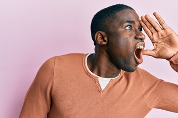 Young african american man wearing casual clothes shouting and screaming loud to side with hand on mouth. communication concept.