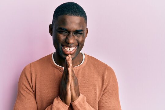 Young african american man wearing casual clothes praying with hands together asking for forgiveness smiling confident.