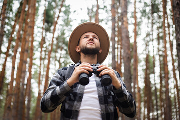 Man with binoculars in the forest. Hike in the mountains or forest