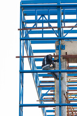 A welder is working on a tall steel building structure